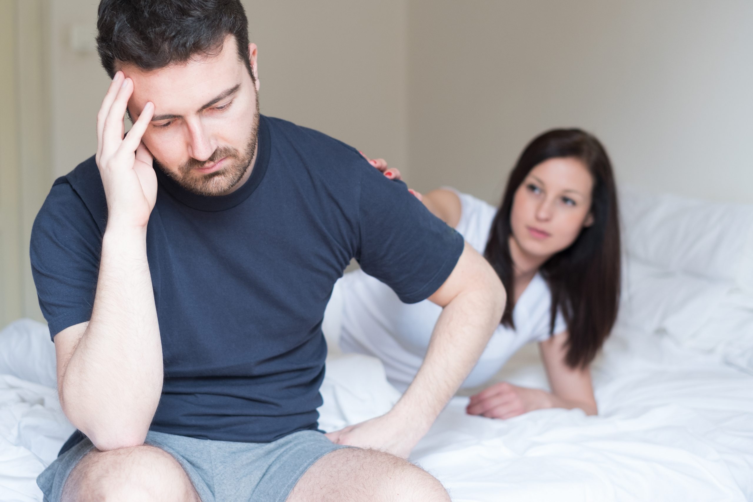 A man sitting infront of his wife in the bed stressed because the problem of erectile dysfuction